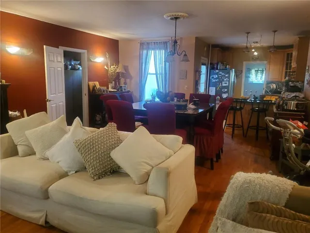 a living room with furniture kitchen view and a wooden floor