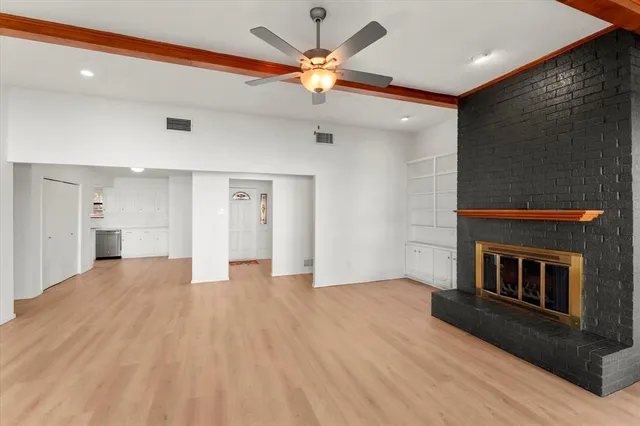 a view of an empty room with a ceiling fan and kitchen view