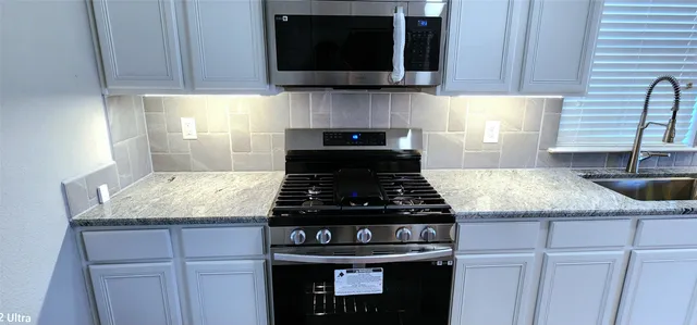 a kitchen with granite countertop a stove and a sink
