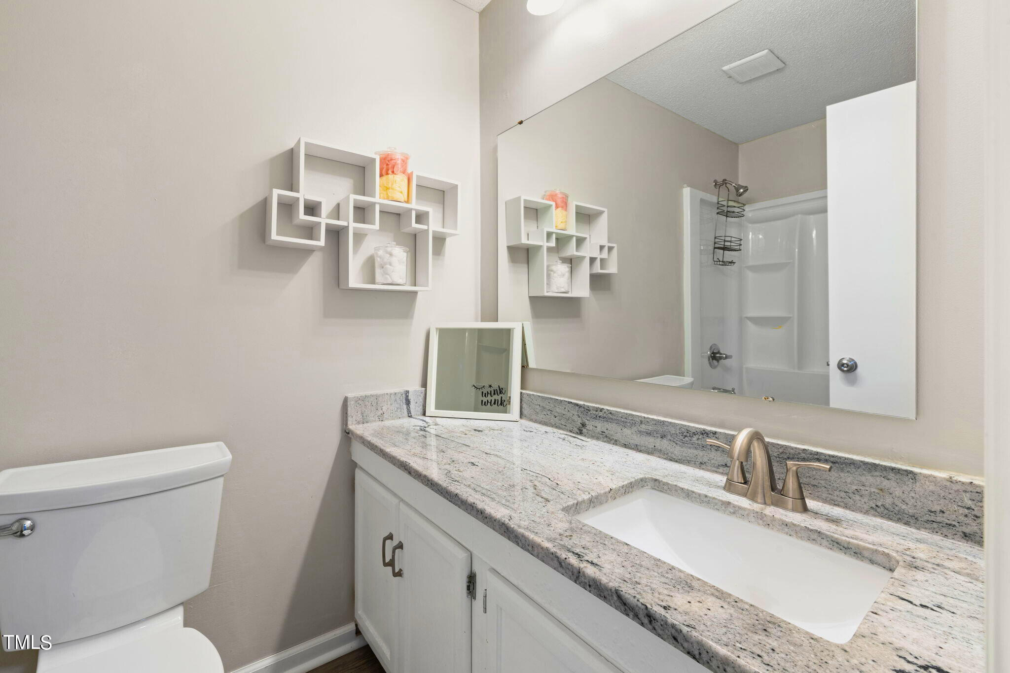 5955 Dixon Drive Raleigh, NC 27609 - Photo 14 of 26 a bathroom with a granite countertop sink a large mirror and a toilet