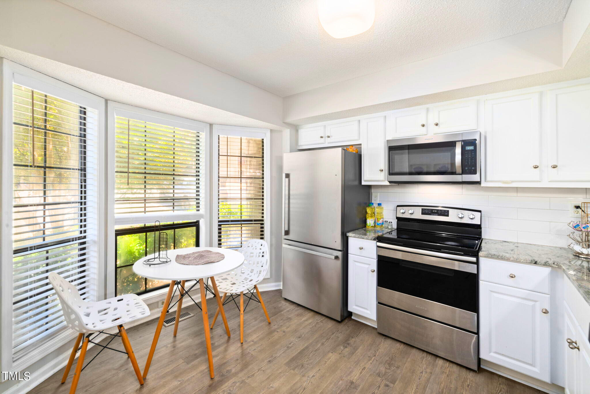 5955 Dixon Drive Raleigh, NC 27609 - Photo 4 of 26 a kitchen with a refrigerator a stove a microwave and dining table