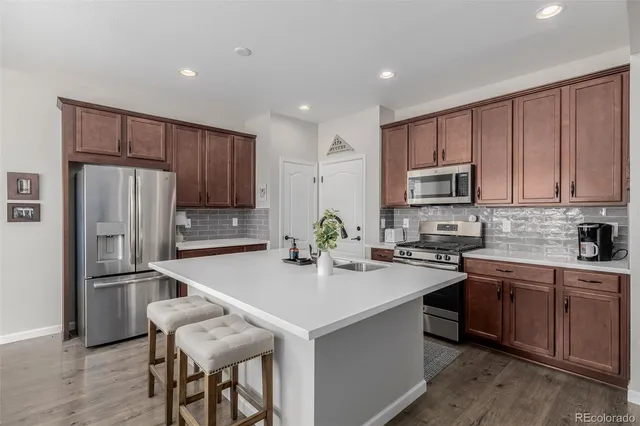 a kitchen with refrigerator a sink and chairs
