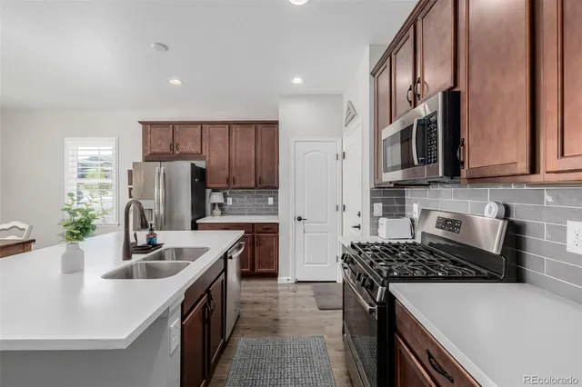 a kitchen with stainless steel appliances granite countertop a sink stove microwave and refrigerator