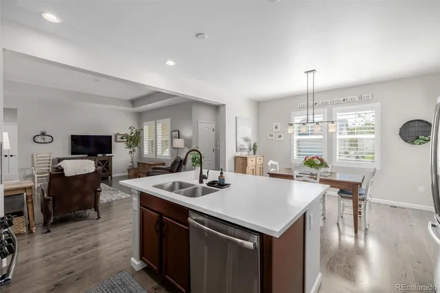 a open kitchen with stainless steel appliances kitchen island granite countertop a stove a sink a dining table and chairs with wooden floor