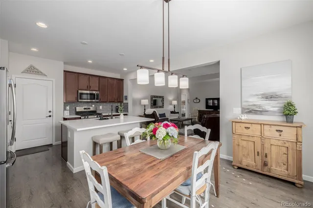 a kitchen with stainless steel appliances granite countertop a stove refrigerator a sink dishwasher a dining table and chairs with wooden floor