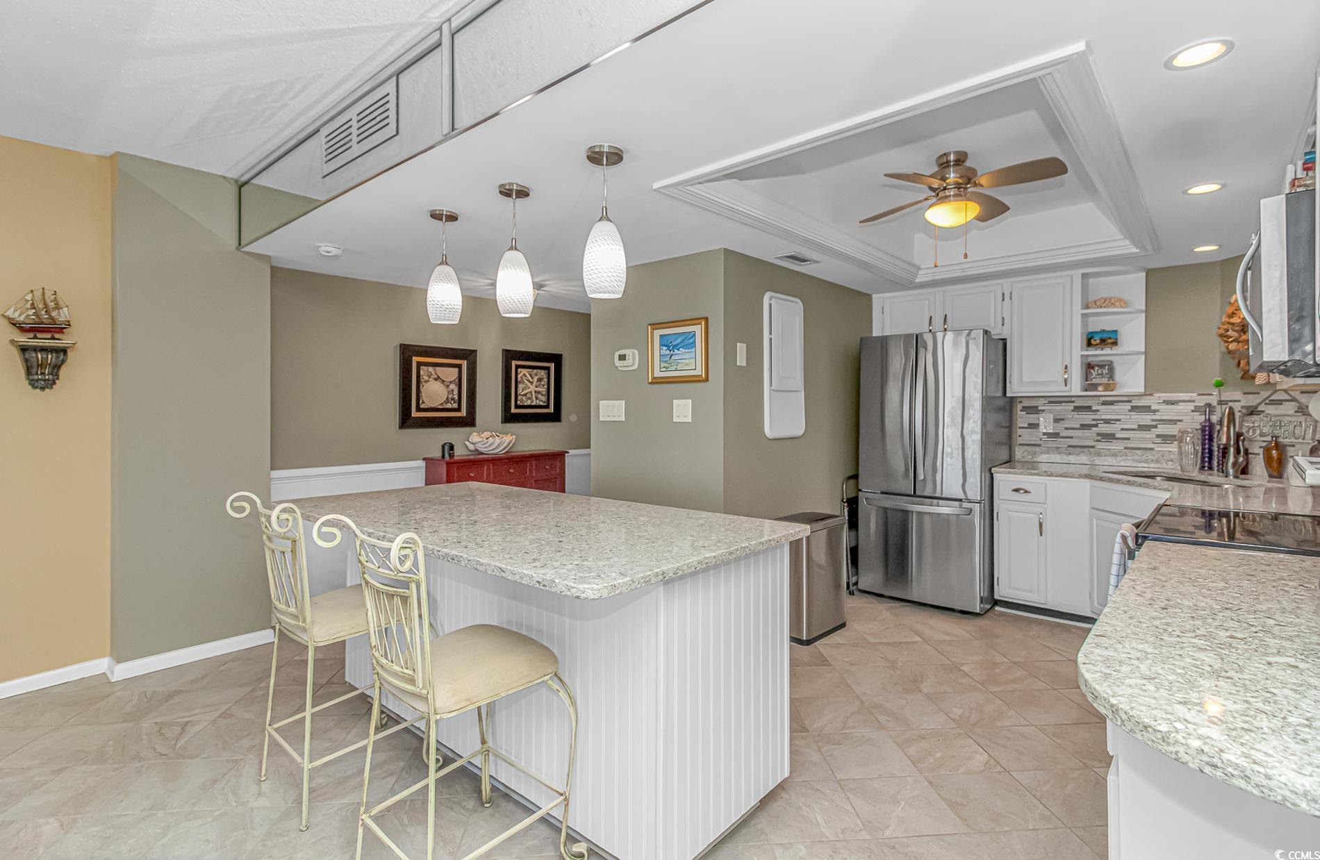 10100 Beach Club Drive, Unit 2B Myrtle Beach, SC 29572 - Photo 4 of 30 Kitchen with a tray ceiling, open shelves, white cabinets, tasteful backsplash, and appliances with stainless steel finishes