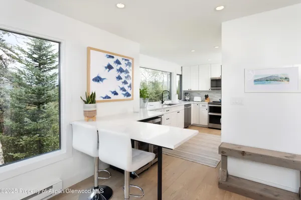 a kitchen with stainless steel appliances kitchen island granite countertop a refrigerator a stove and white cabinets with wooden floor