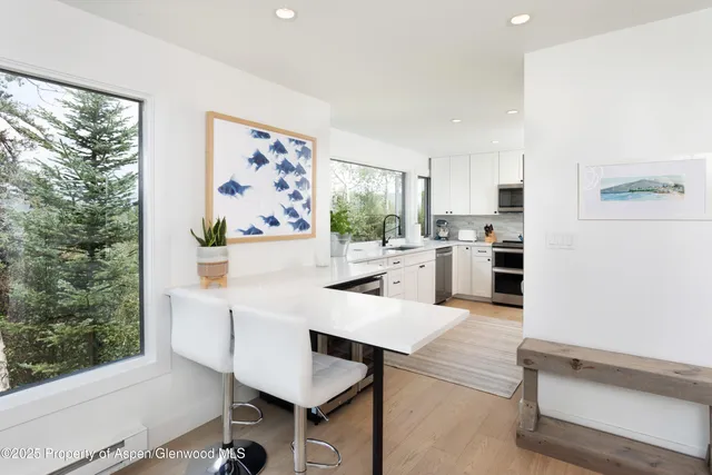 a kitchen with stainless steel appliances kitchen island granite countertop a refrigerator a stove and white cabinets with wooden floor