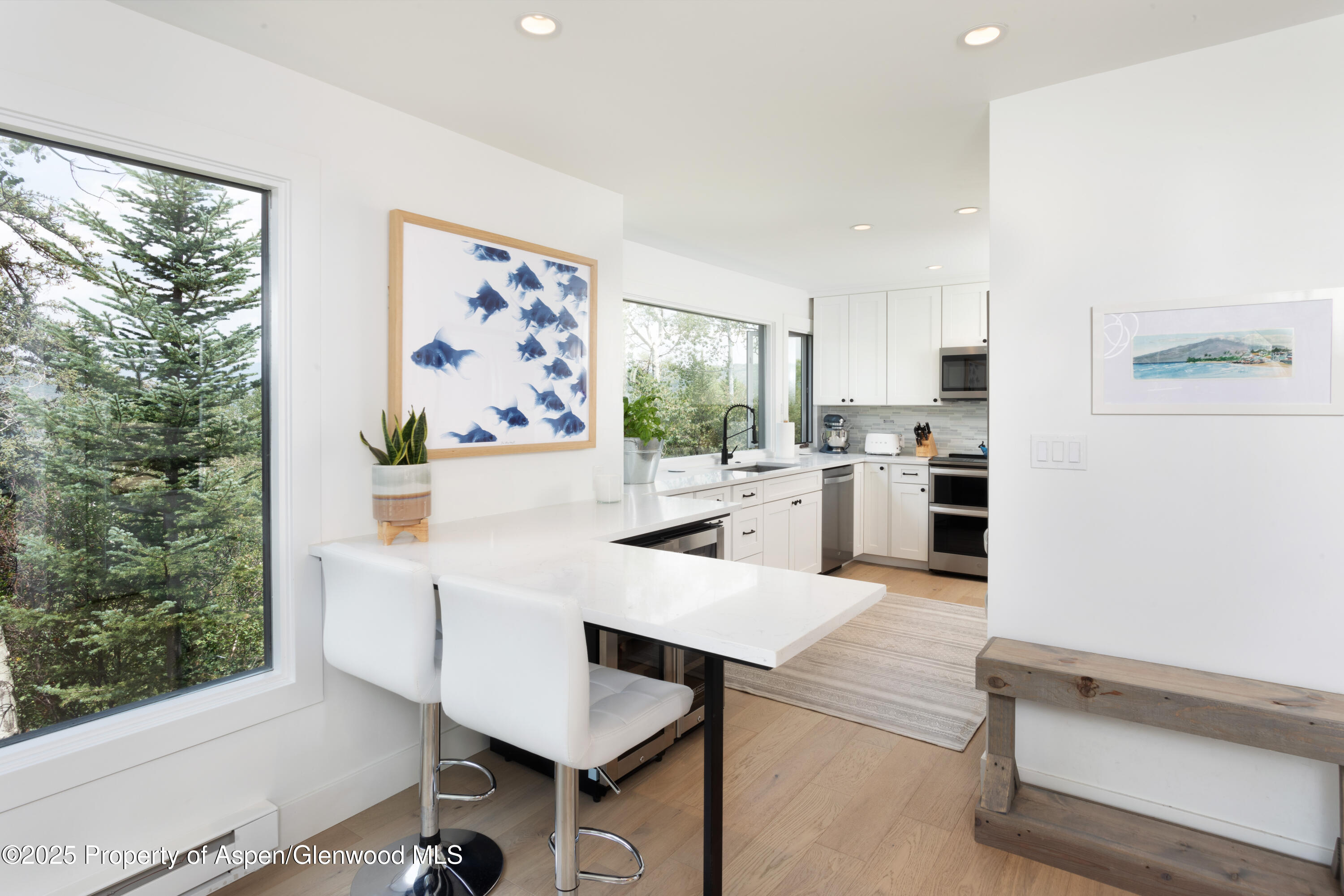 145 North Ridge Lane, Unit 2 Snowmass Village, CO 81615 - Photo 10 of 22 a kitchen with stainless steel appliances kitchen island granite countertop a refrigerator a stove and white cabinets with wooden floor