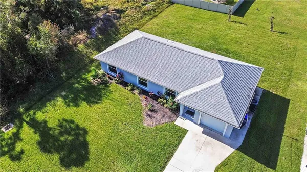 a aerial view of a house next to a yard with large tree