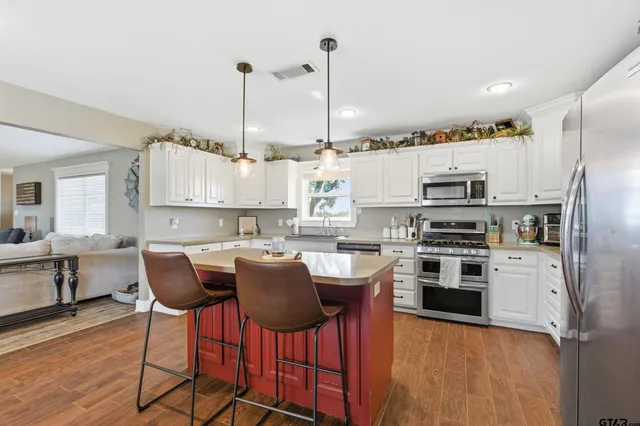 a kitchen with stainless steel appliances a stove a sink refrigerator and a chair