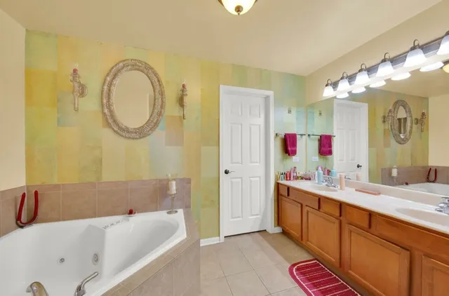 a bathroom with a tub a double vanity sink and a mirror