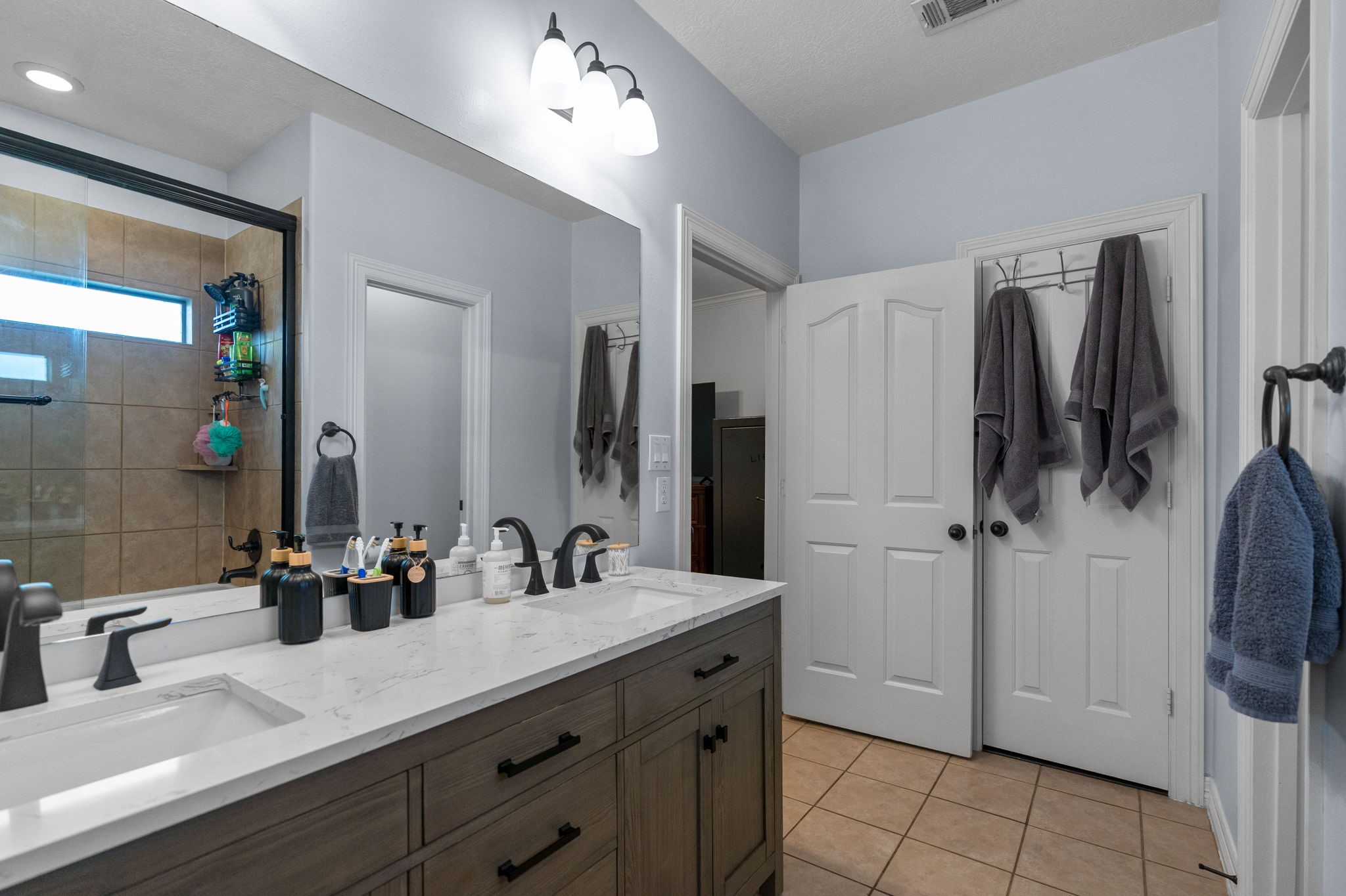 5942 Wildflower Road Sealy, TX 77474 - Photo 15 of 41 a bathroom with a double vanity sink a mirror and shower