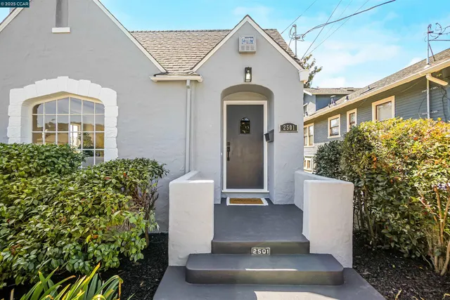 a view of a white house with potted plants
