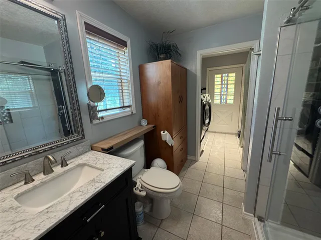 a bathroom with a granite countertop sink toilet and shower a mirror