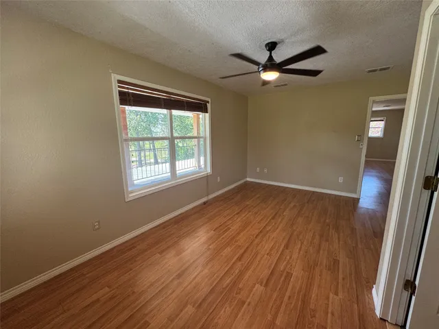 a view of empty room with wooden floor and fan
