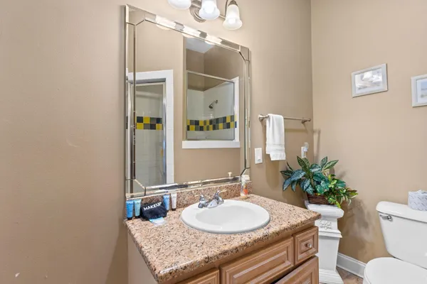 a bathroom with a granite countertop sink and a mirror with toilet