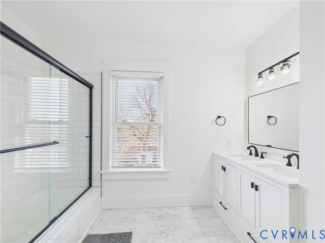 a bathroom with a double vanity sink a mirror and next to a window