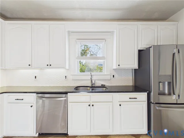 a kitchen with granite countertop white cabinets white stainless steel appliances and a sink