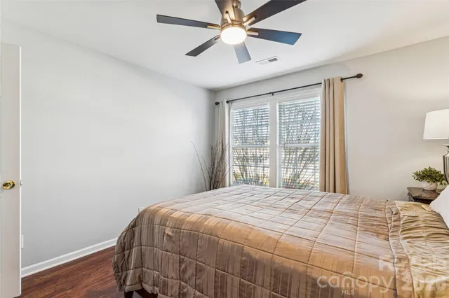 a view of a white house next to a road with big trees