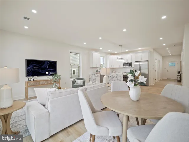 a living room with stainless steel appliances furniture and a dining table with wooden floor