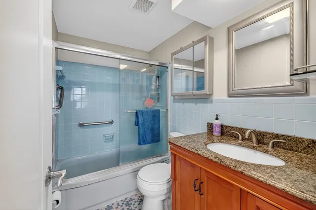 a bathroom with a granite countertop sink toilet and shower