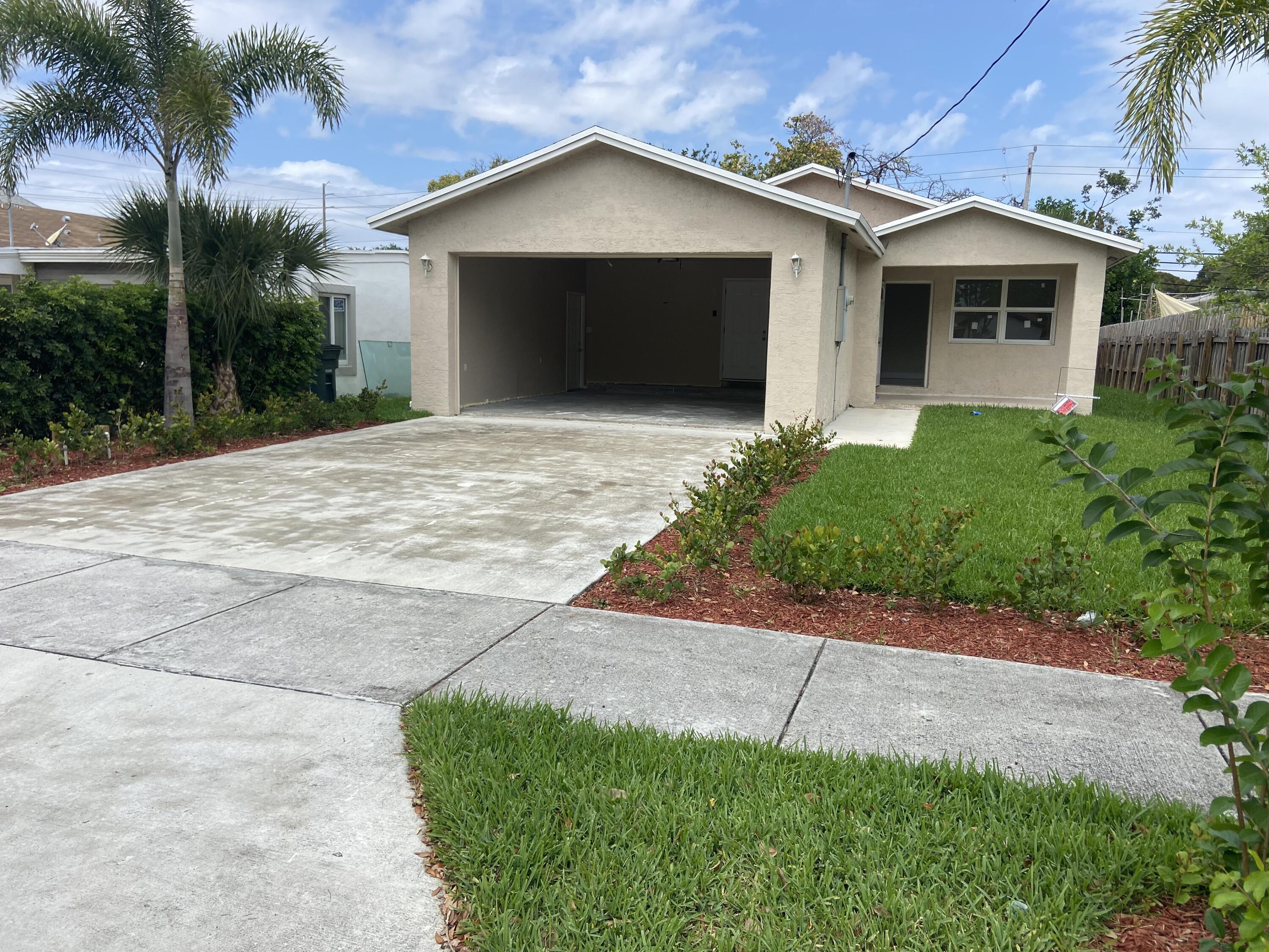 171 Northeast 15th Terrace Boca Raton, FL 33431 - Photo 2 of 2 a front view of a house with a yard and garage
