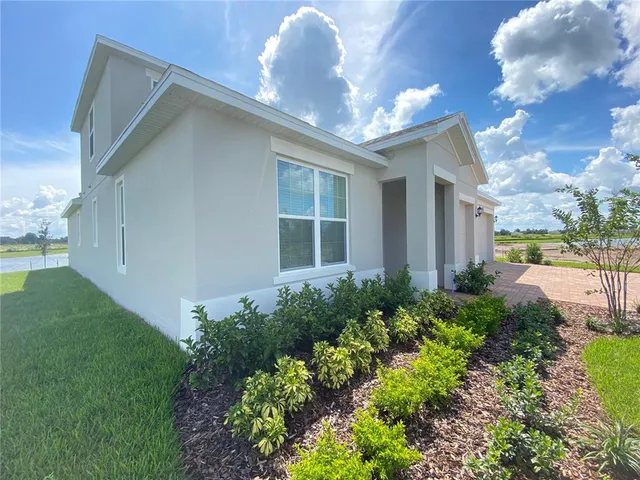 a view of a house with a big yard and large windows