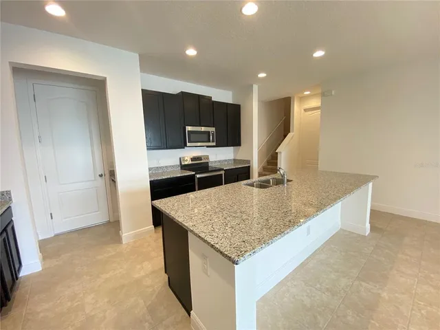 a kitchen with stainless steel appliances granite countertop a sink and a refrigerator