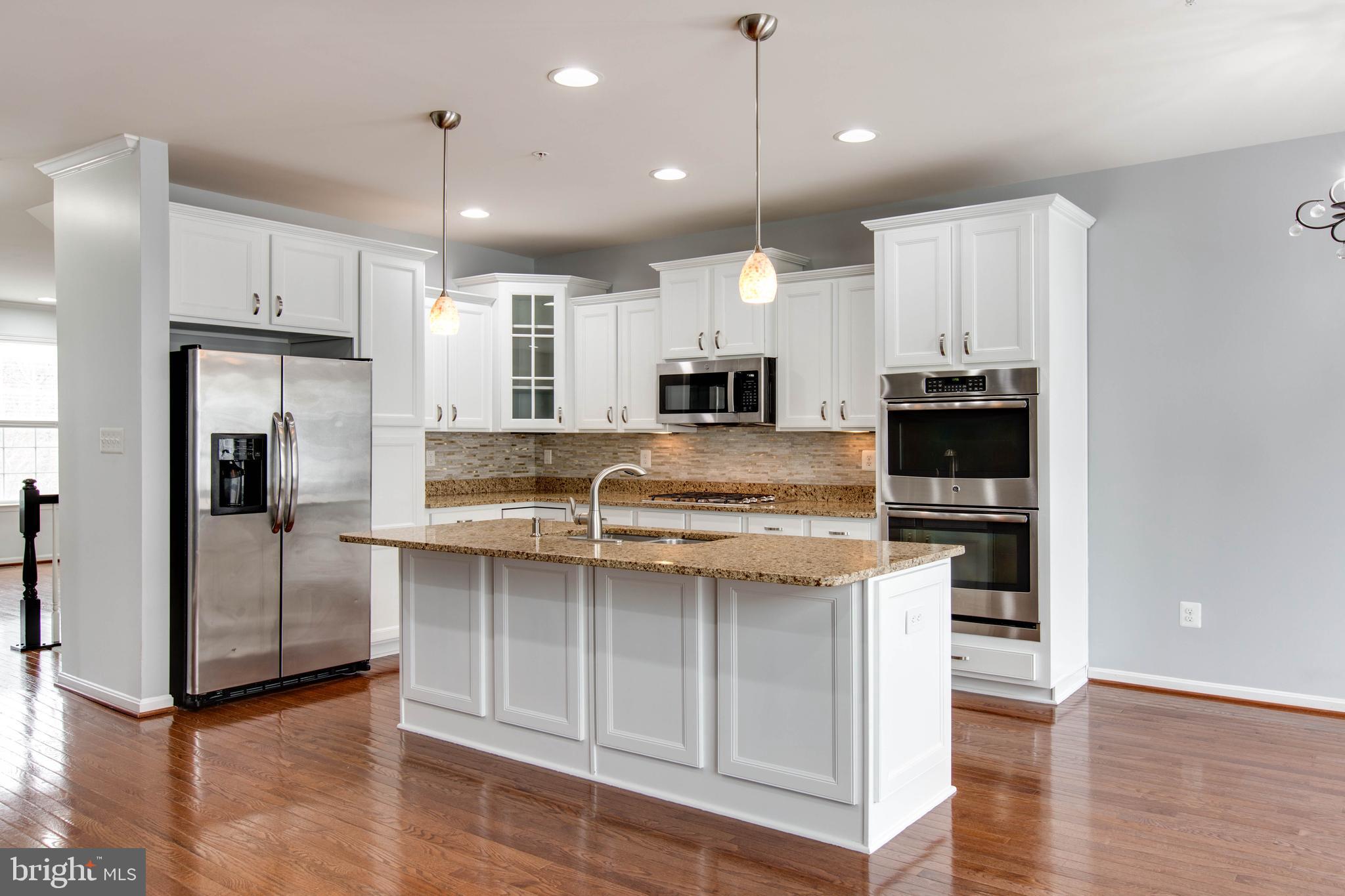7926 Silver Oak Road Hanover, MD 21076 - Photo 16 of 44 an open kitchen with white cabinets and stainless steel appliances
