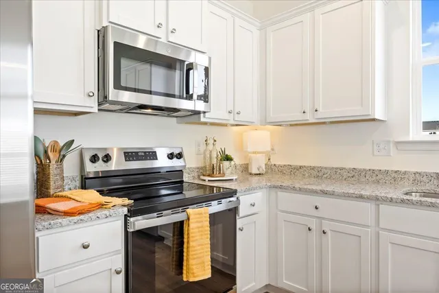 a kitchen with stainless steel appliances granite countertop a refrigerator stove and white cabinets