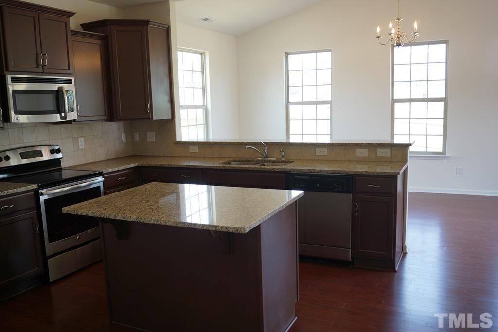 2740 Shepherd Valley Street Raleigh, NC 27610 - Photo 7 of 15 a kitchen with granite countertop a stove a sink and a microwave