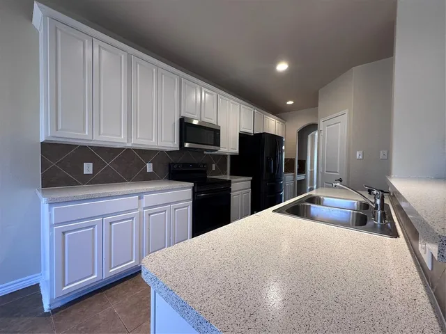 a kitchen with kitchen island granite countertop a sink stainless steel appliances and cabinets
