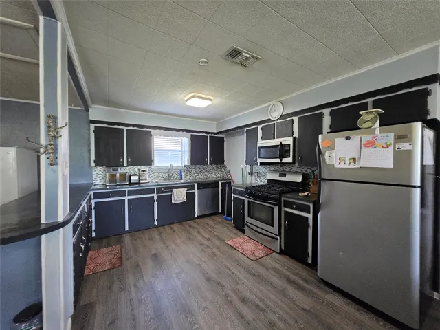 a kitchen with stainless steel appliances kitchen island granite countertop a refrigerator stove and sink