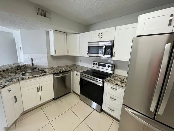 a kitchen with granite countertop cabinets appliances and a sink