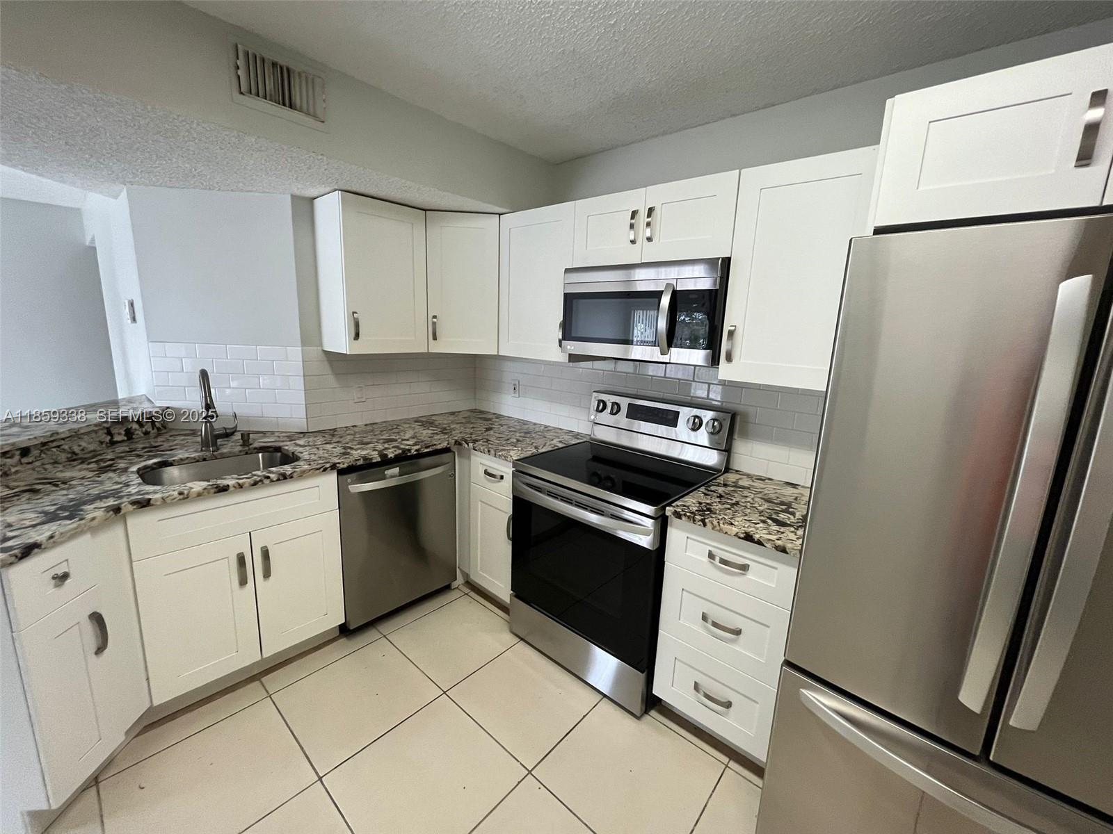 8821 Wiles Road, Unit 203 Coral Springs, FL 33067 - Photo 1 of 30 a kitchen with granite countertop cabinets appliances and a sink