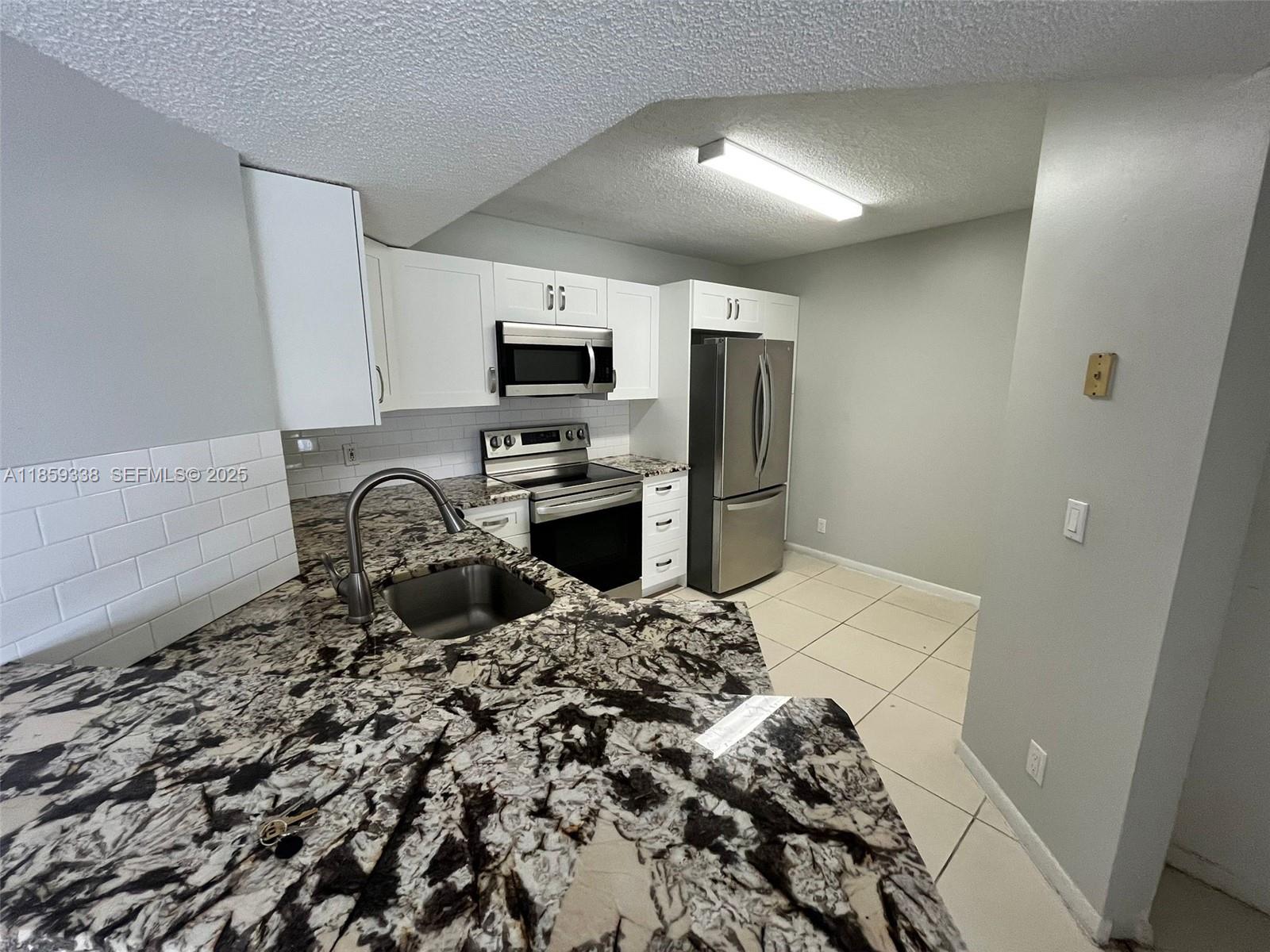 8821 Wiles Road, Unit 203 Coral Springs, FL 33067 - Photo 2 of 30 a kitchen with a refrigerator and a sink