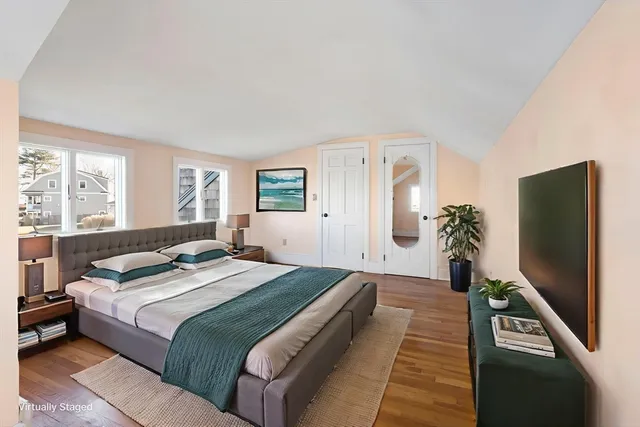 a bedroom with a large bed and a flat tv screen on dresser