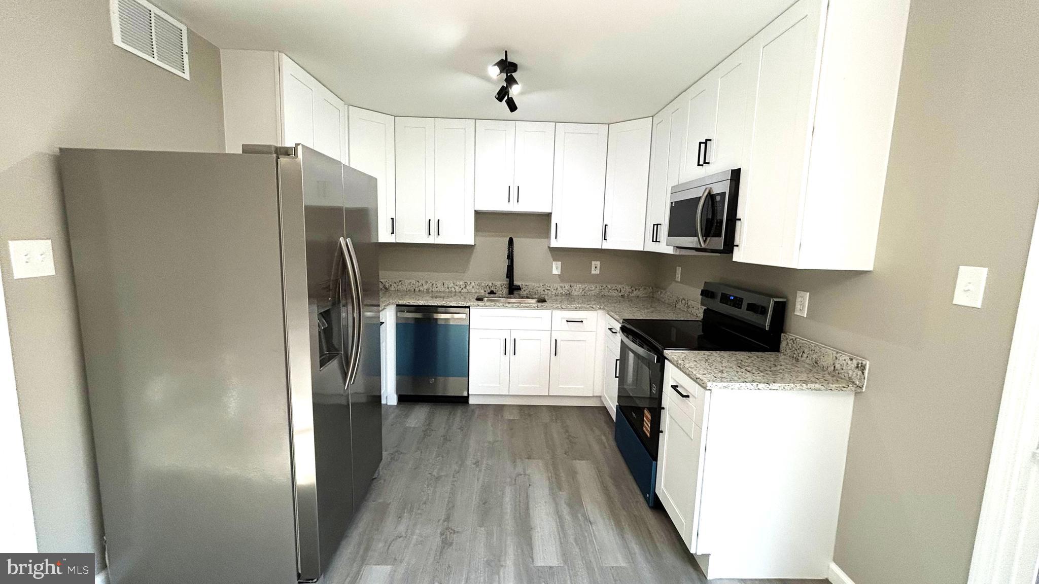 a kitchen with stainless steel appliances a refrigerator sink and white cabinets