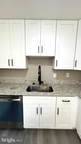 a kitchen with granite countertop white cabinets and sink