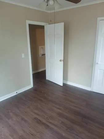 a view of an empty room with wooden floor and closet