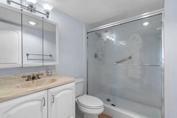 a bathroom with a granite countertop sink toilet and shower