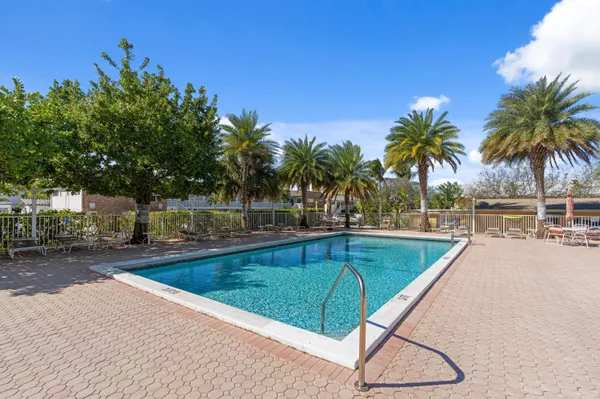 a view of a swimming pool with a lounge chair and palm trees