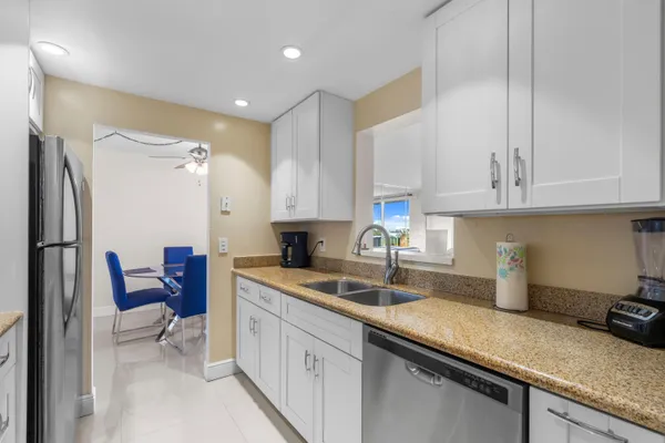 a kitchen with a sink dishwasher a refrigerator and cabinets with wooden floor