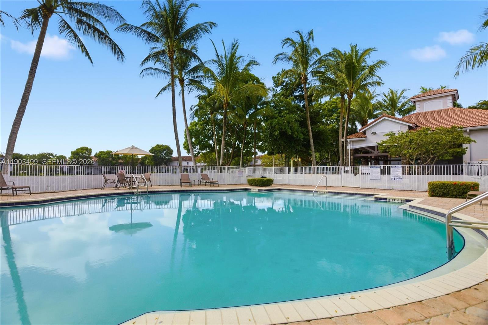 8231 Southwest 29th Street Miramar, FL 33025 - Photo 44 of 53 a view of a swimming pool with a lawn chairs under palm trees