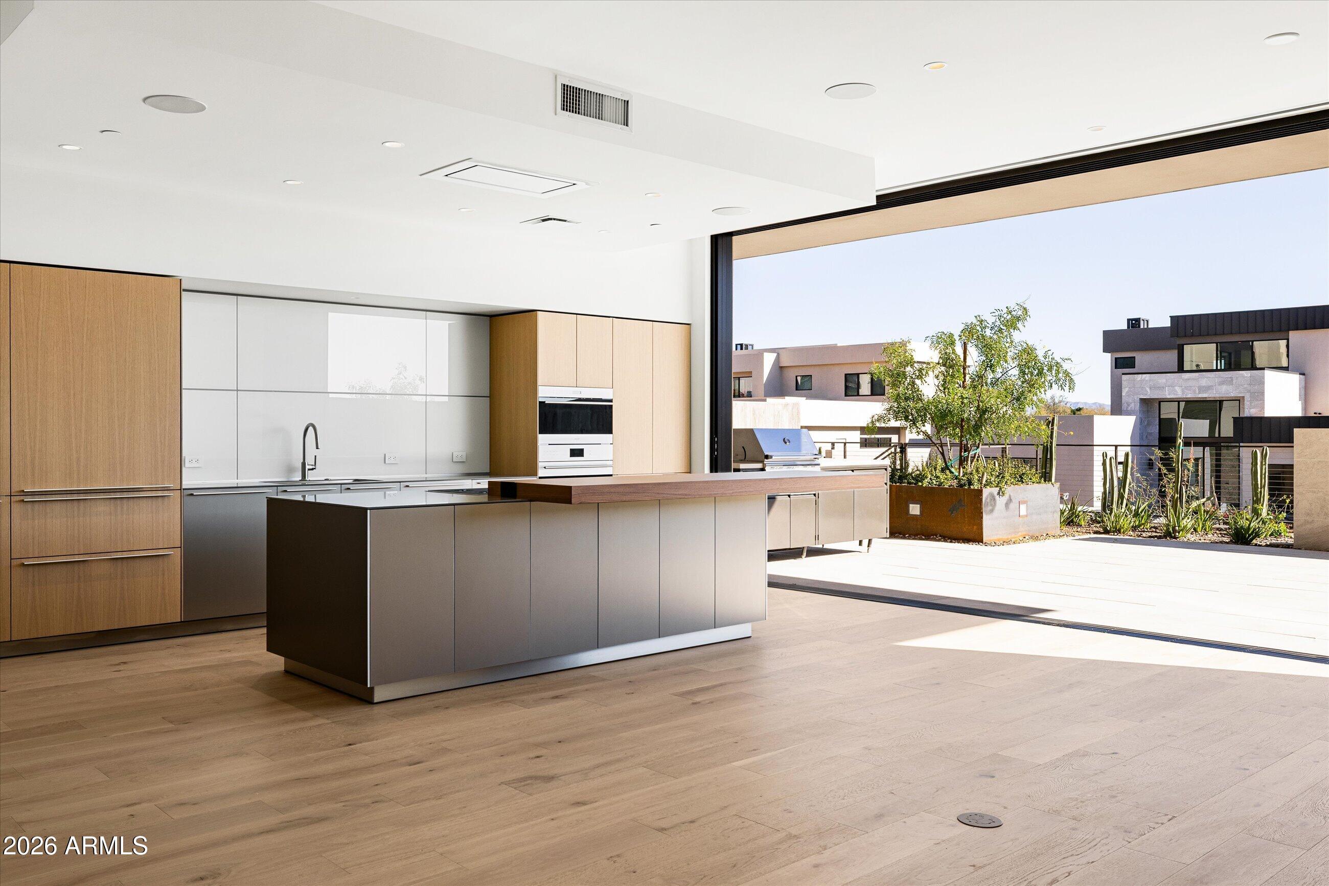 4849 North Camelback Ridge Road, Unit B104 Scottsdale, AZ 85251 - Photo 10 of 41 a kitchen with stainless steel appliances kitchen island granite countertop a refrigerator a stove and a wooden floors