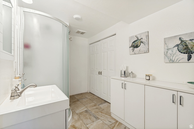 9832 Falconhurst Drive Sandy, UT 84092 - Photo 23 of 29 Compact bathroom featuring a curved frosted-glass shower enclosure, a white vanity with an integrated sink, and brushed nickel fixtures