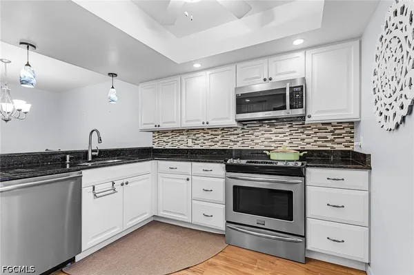 a kitchen with granite countertop a sink cabinets and stainless steel appliances