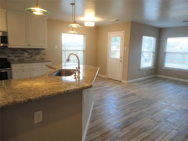 a bathroom with a granite countertop sink a light fixture and a mirror