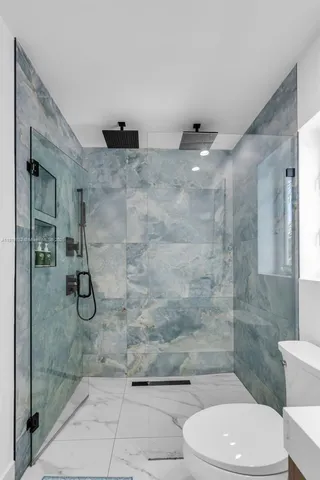 a bathroom with a granite countertop shower a toilet and sink